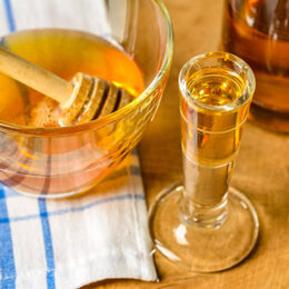 Mead - honey wine in a testing glass with a bowl of honey.